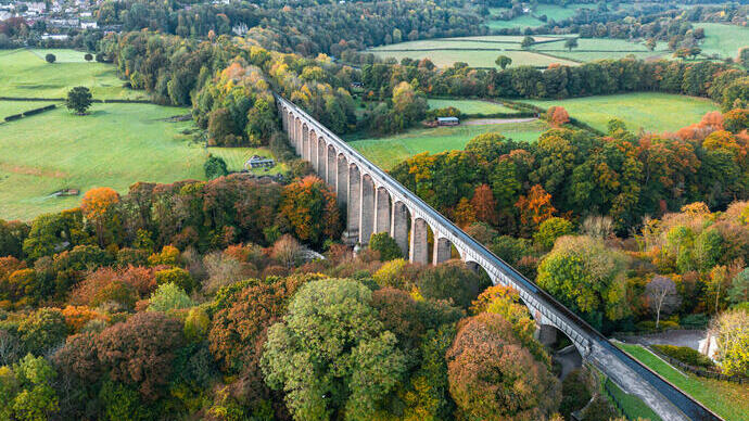 Aerial view of a long viaduct spanning river in an autumnal setting