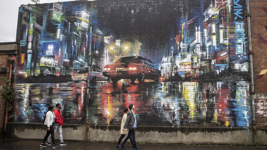 People looking at mural on city building