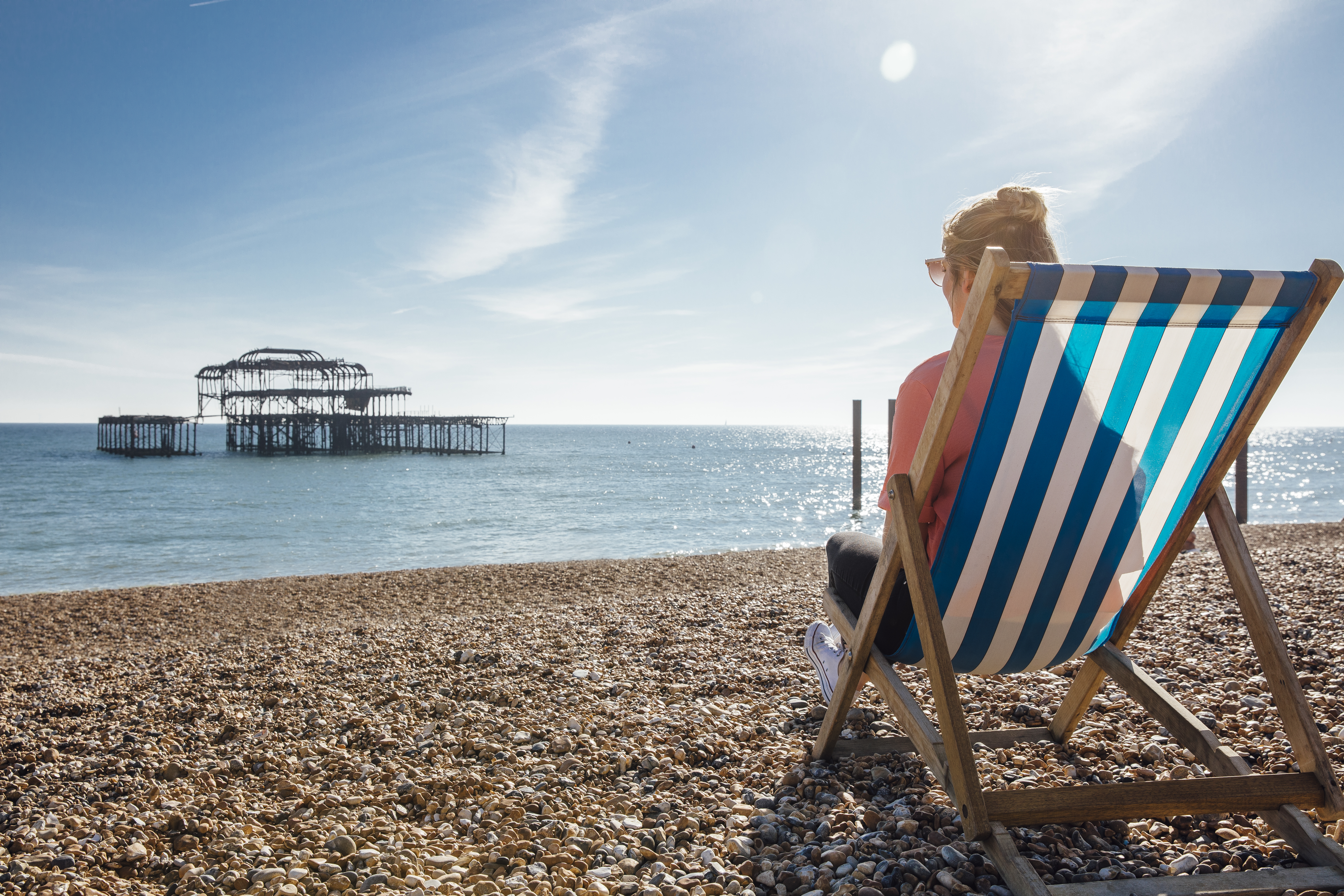 Woman sitting in a striped deckchair on a beach