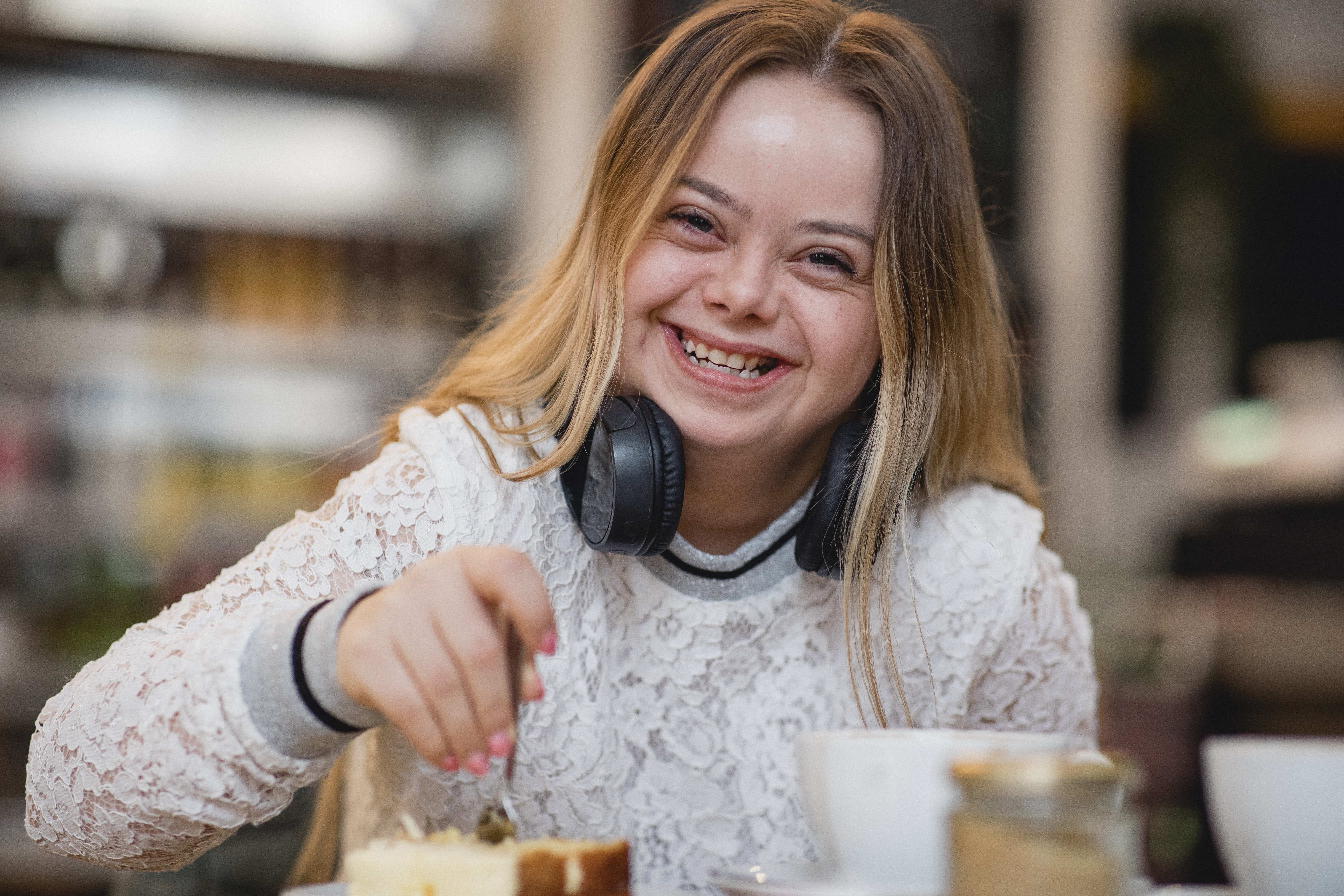 Young female with Down's Syndrome sat at a table laughing