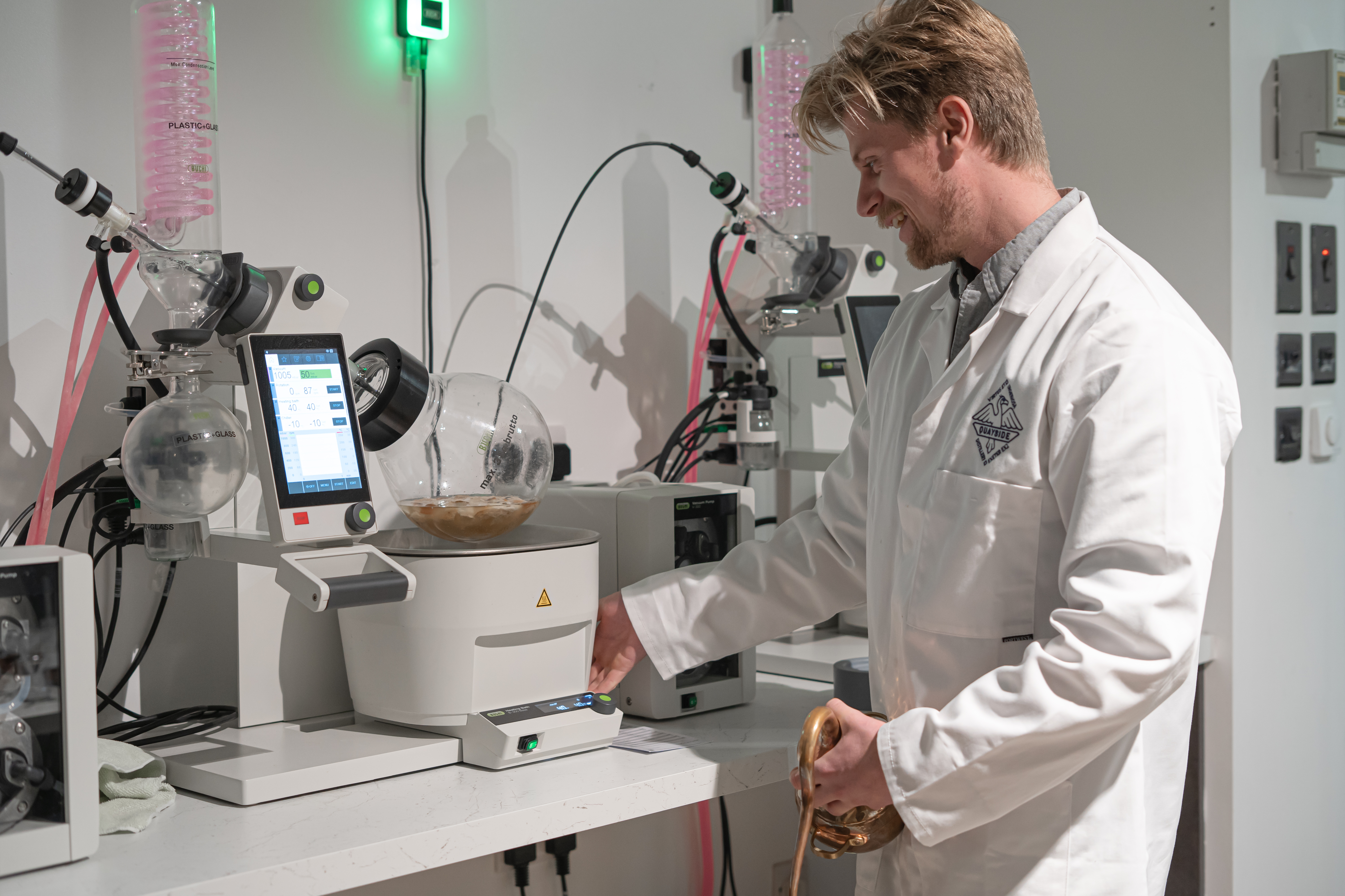 Un hombre con bata de laboratorio utilizando una máquina de destilación