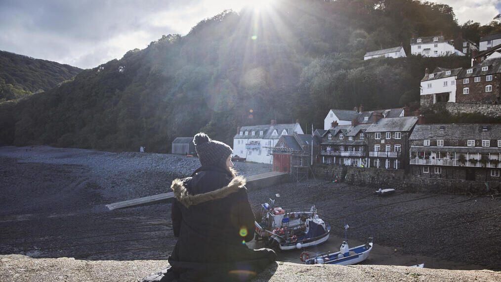 Woman sitting on harbour wall in the sunshine