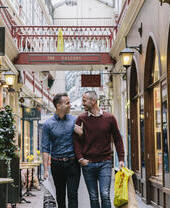 Couple d'hommes marchant bras dessus bras dessous dans une galerie marchande victorienne