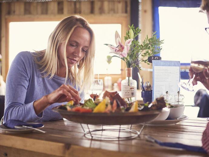 Mujer rubia y hombre sentados a la mesa, comiendo una bandeja de marisco