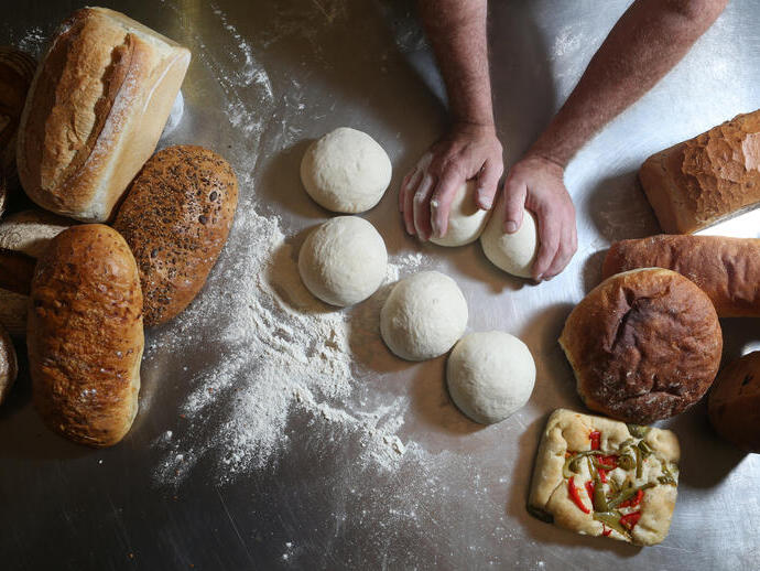 Fresh baked goods being prepared by a baker.