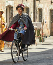 Donna vestita con un costume da infermiera degli anni '50 in sella a una bicicletta