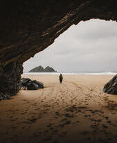 Une femme marche dans une grotte sur une plage