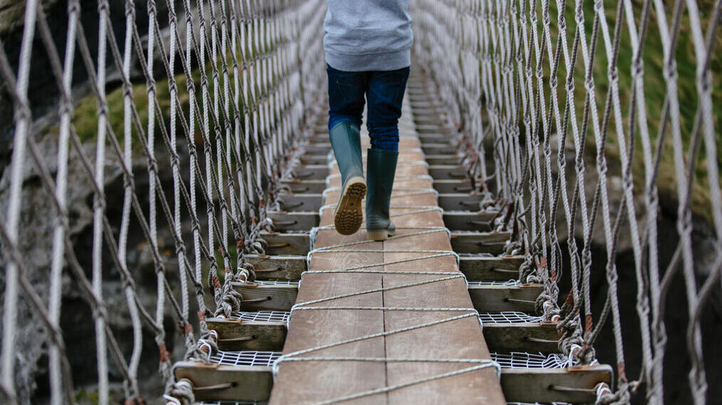 Child walking on a long rope bridge.