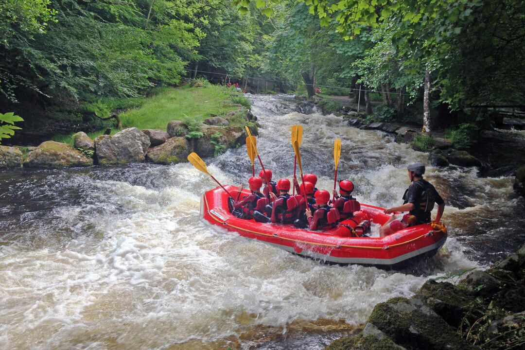 مجموعة من الأطفال في زورق كبير مع مدرب ينزلون بعض المنحدرات المائية