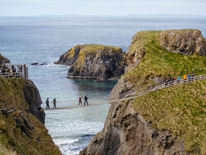 People crossing a rope bridge over the sea