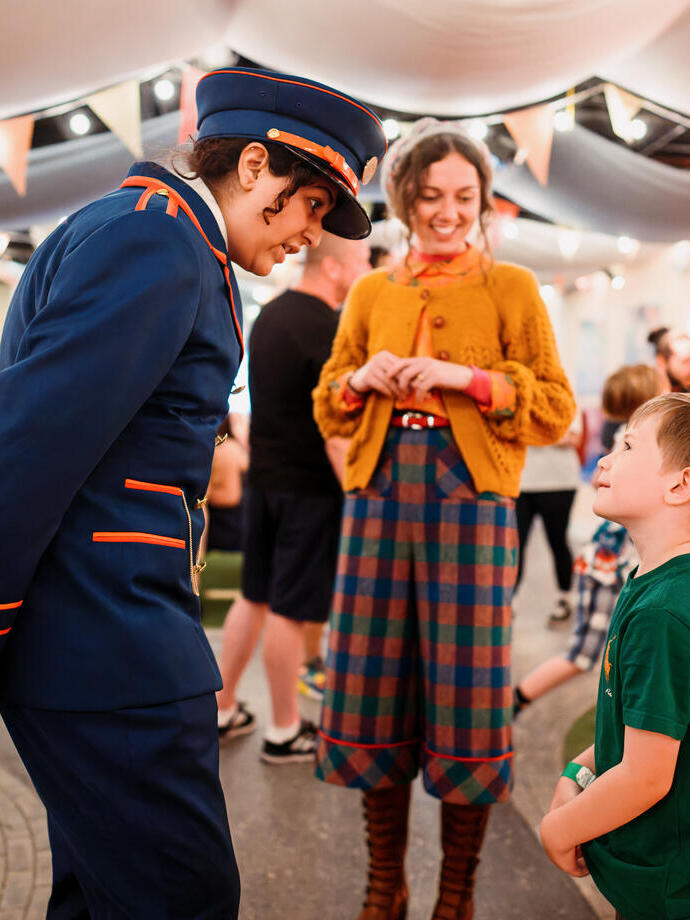 Des acteurs en costume discutent avec un jeune enfant.