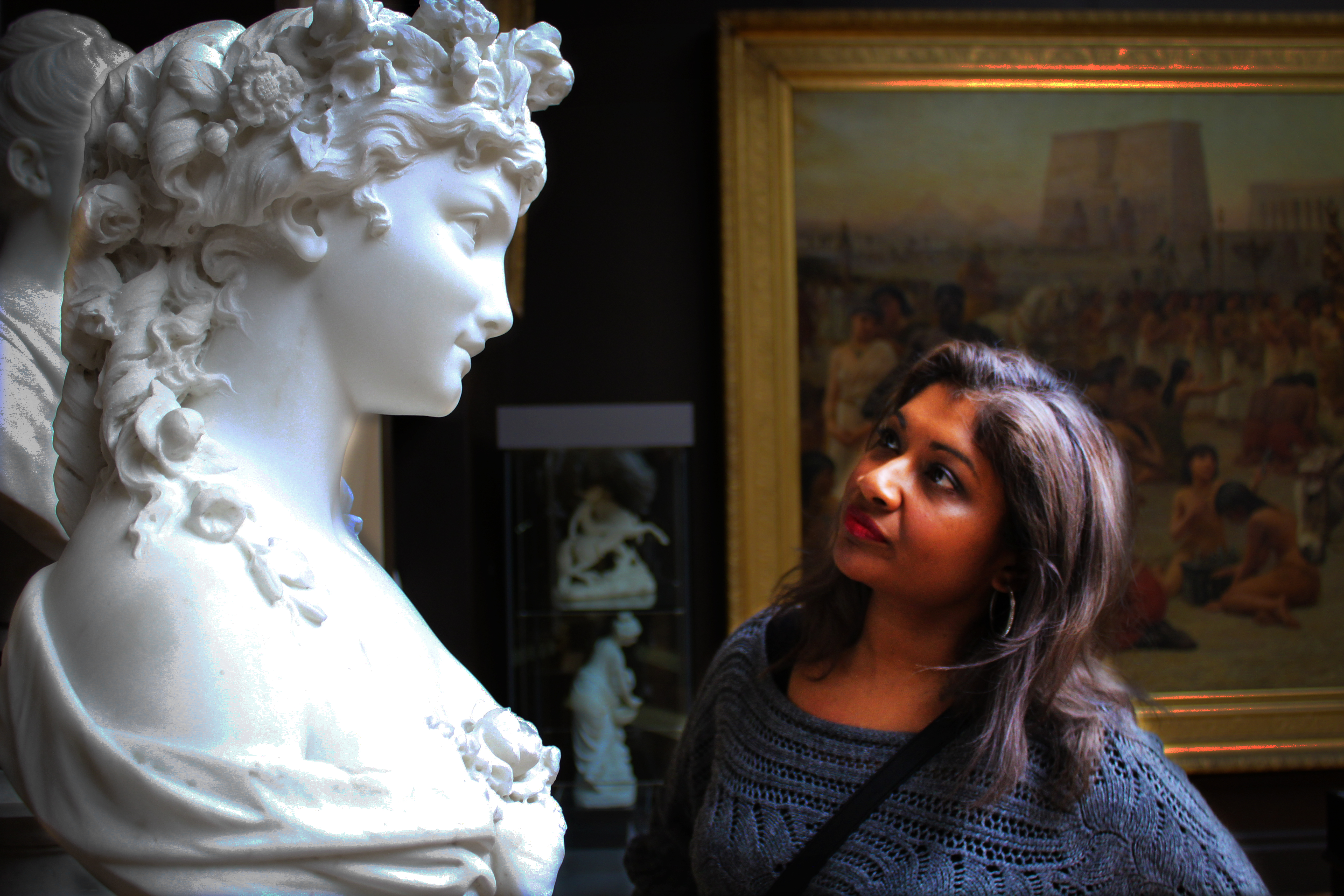 A woman looking at a sculpture on a pedestal in an art gallery