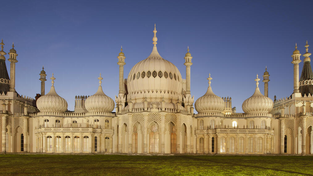 Large palace with white domes and minarets at night