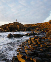 Man standing on a rock formation on the edge of the sea