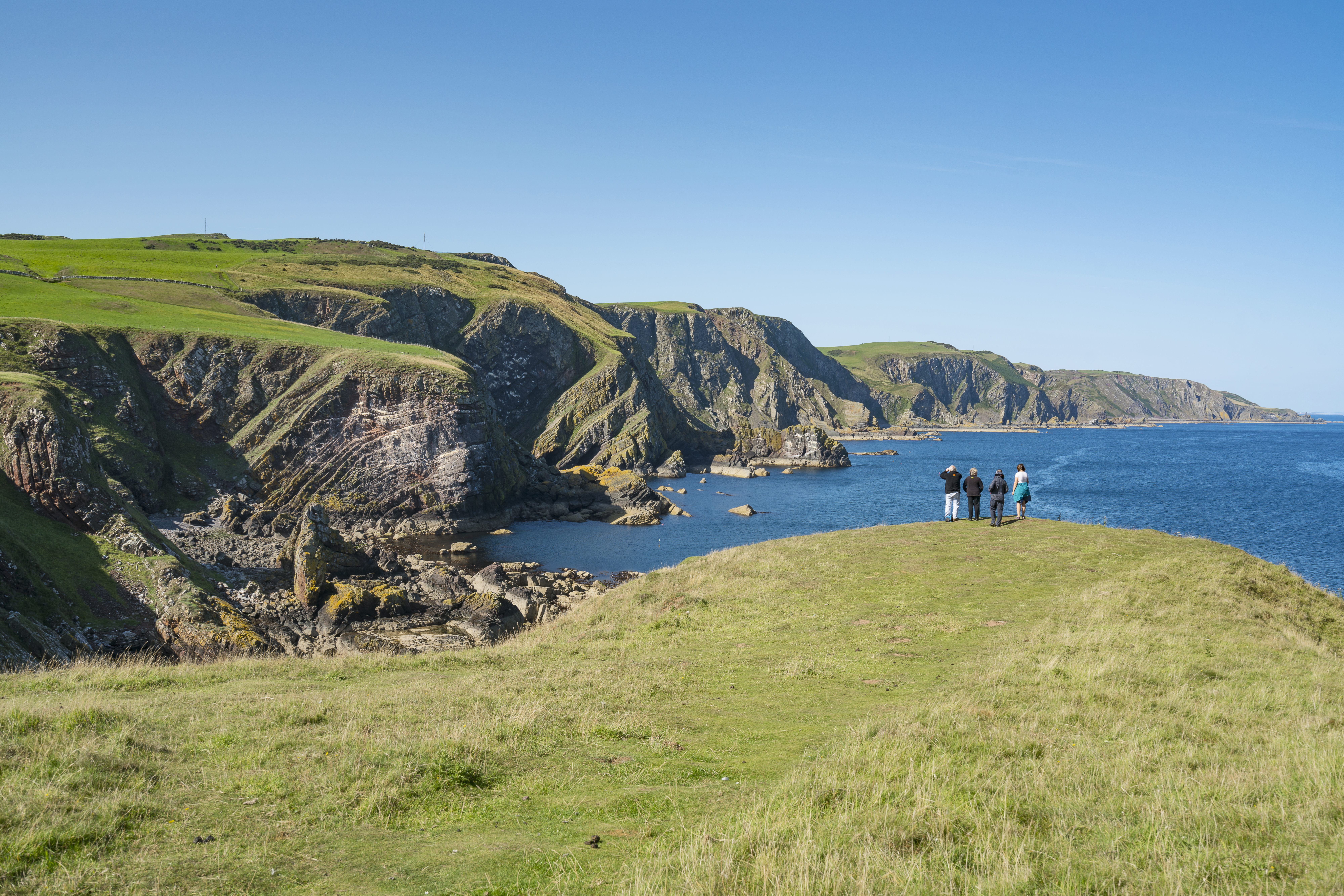 Group of people on a cliff looking at a bay