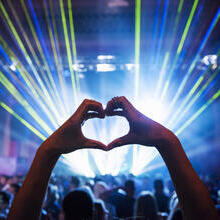 Woman making heart shape with hands at a music event
