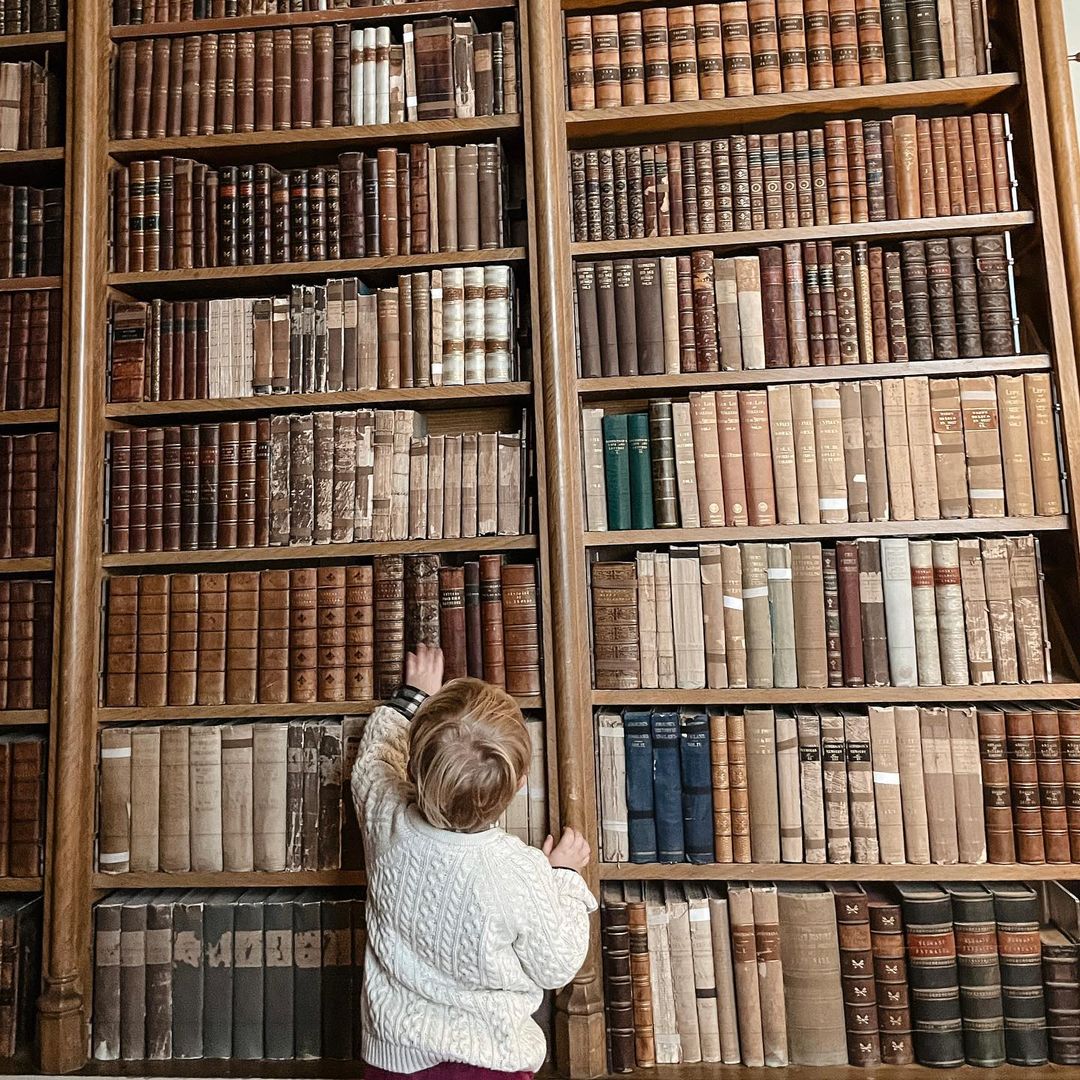 A young visitor looks up at a large book case