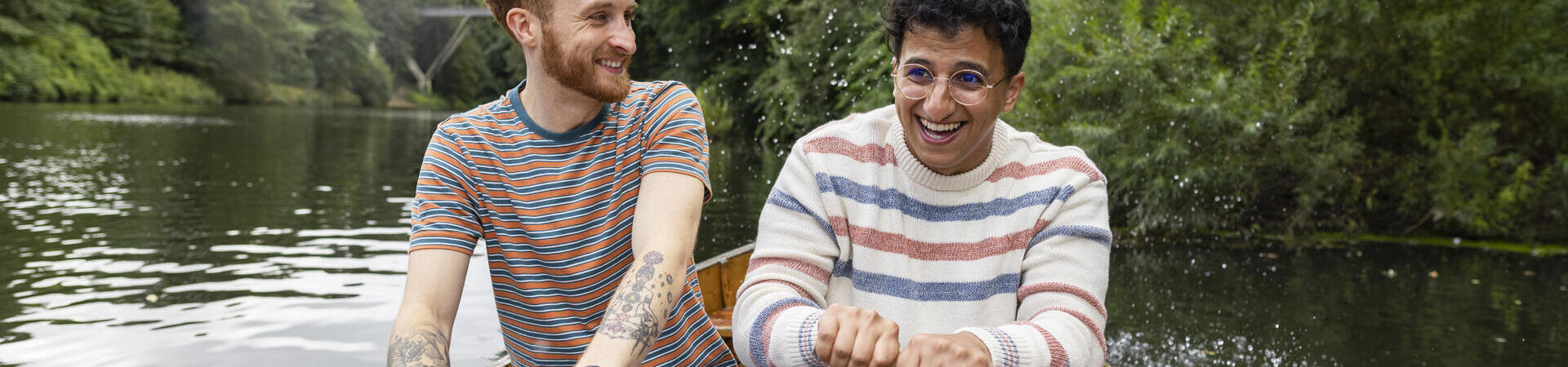 A male couple sitting in a rowboat, rowing together
