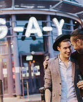 Pareja gay abrazándose a la entrada de un bar