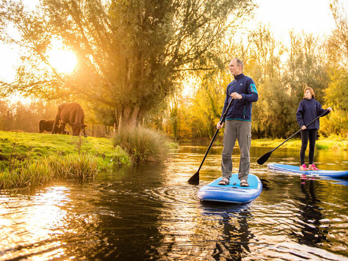 Two people paddleboarding down the River Bure