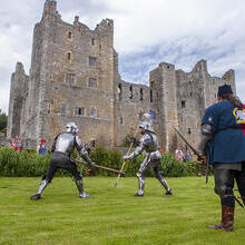 Two men in full knight armor putting on a performance for a watching crowd at Bolton Castle, Yorkshire