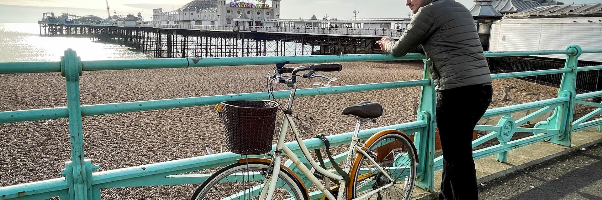 Mann, der mit einem Fahrrad an einem Geländer am Meer lehnt