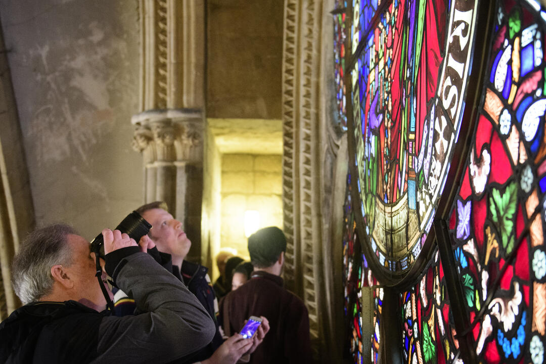 A tour group on a tour of Lincoln Cathedral, looking at a stained glass window
