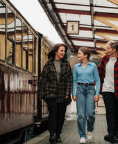 Three people walking along a train platform.