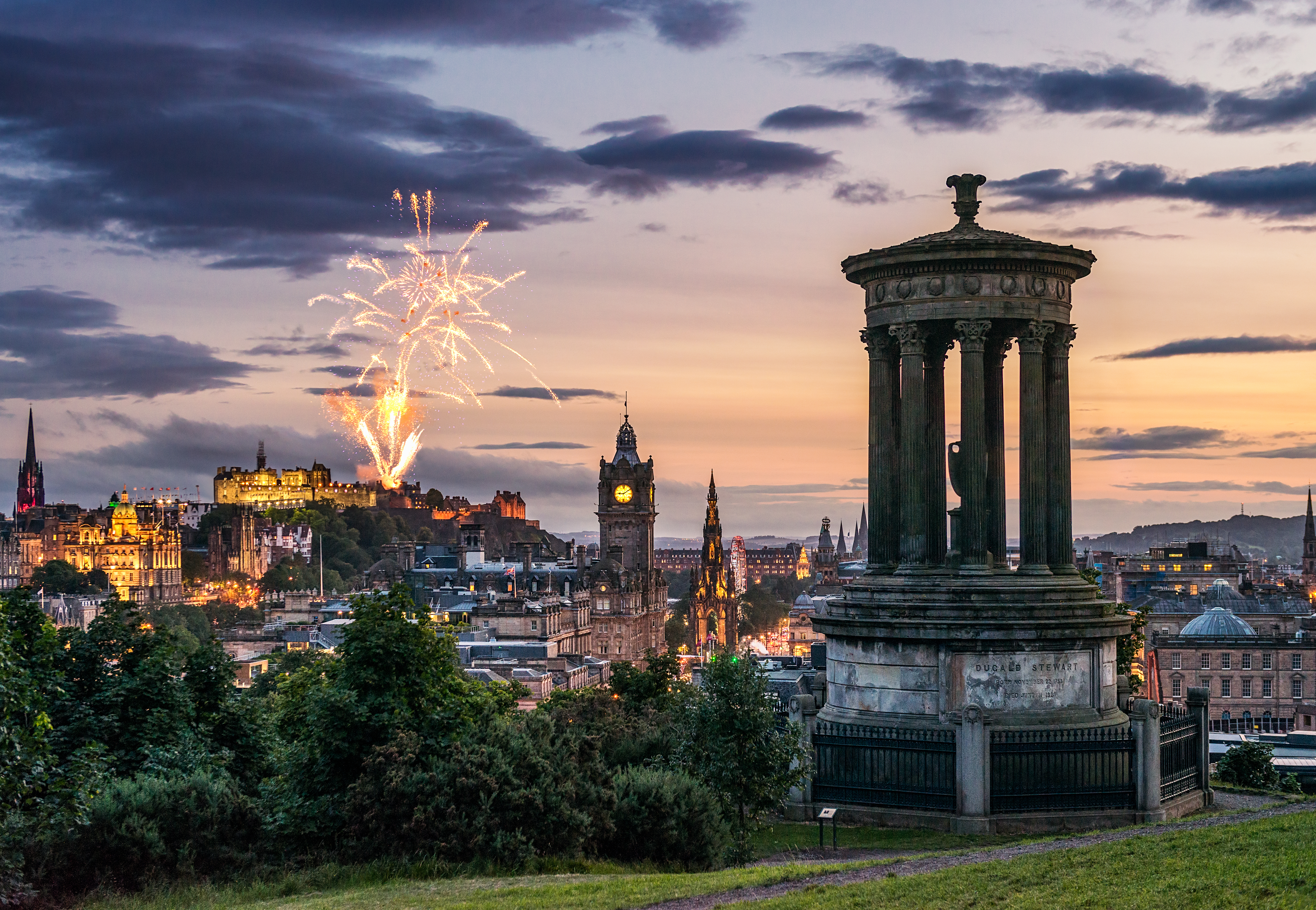 Fireworks at dusk in the sky over city monuments