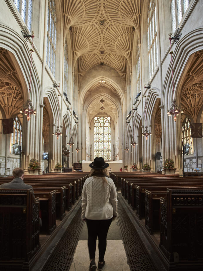 Woman walking down the aisle of an abbey