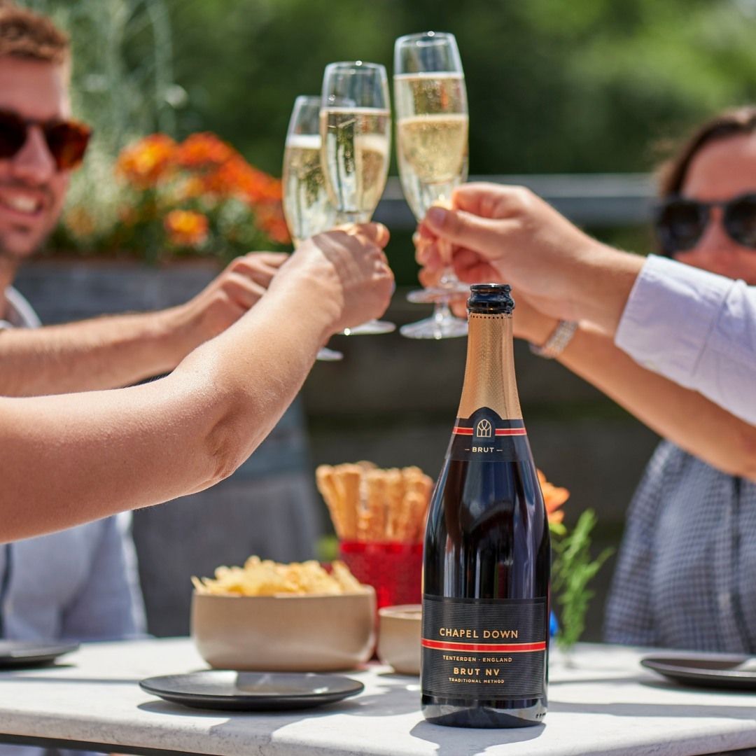 Un grupo de personas sentadas a una mesa brindando en la bodega Chapel Down