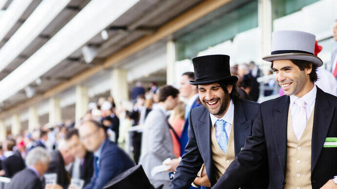 Men dressed smartly and wearing top hats in a grandstand laughing