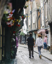 A man and a woman walk down a cobbled street holding hands