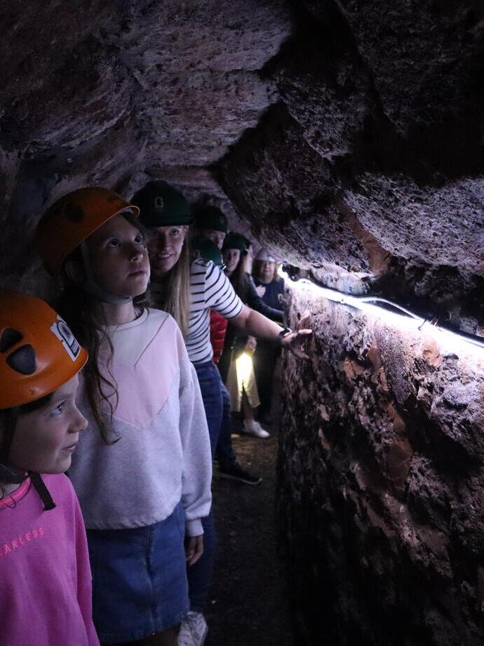 A group of children in helmets exploring an underground passage