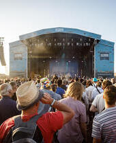 A large crowd enjoying a band on stage at an outdoor concert.