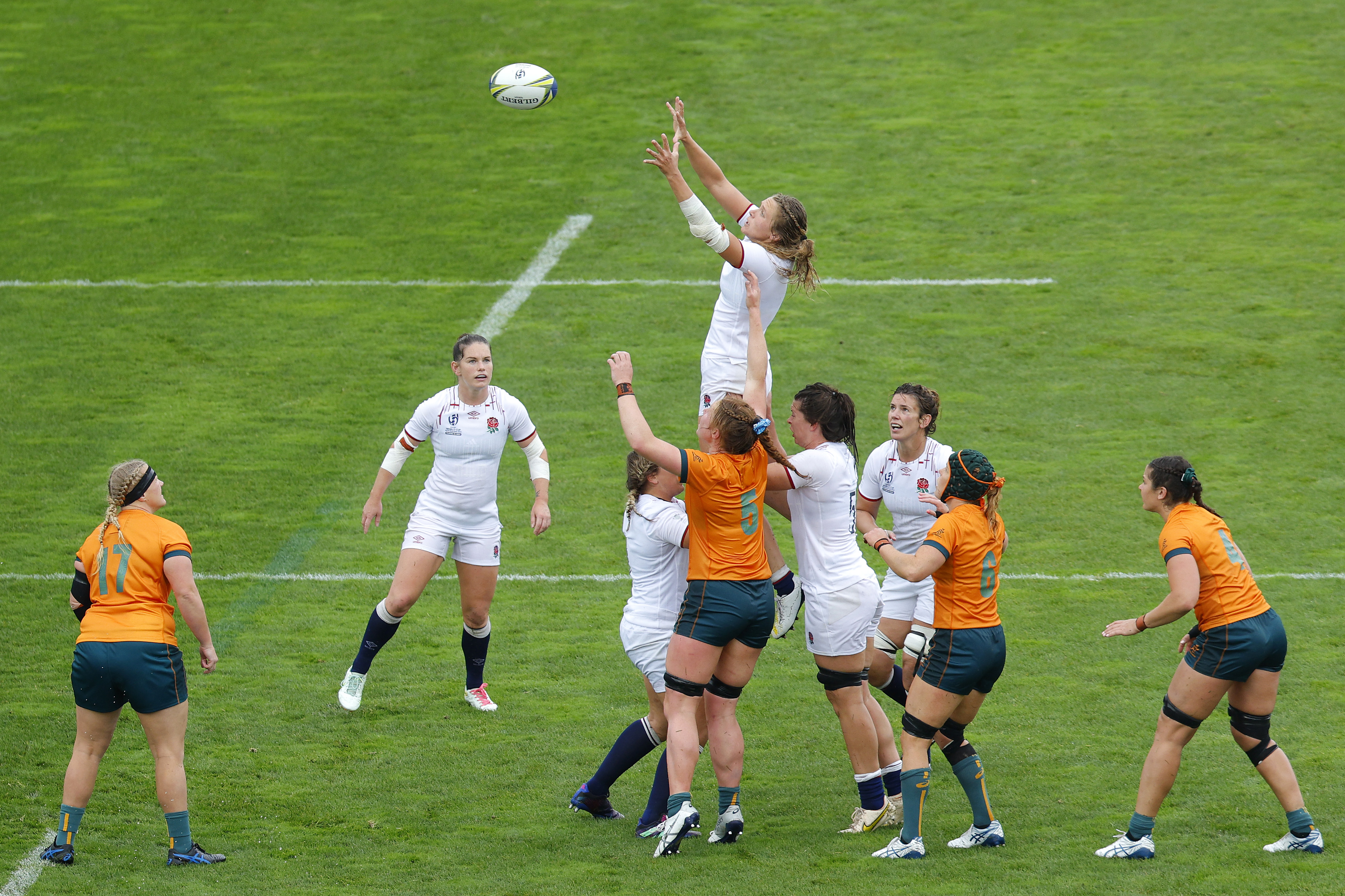 Women's rugby match with players from two teams jumping to catch the ball on the field
