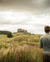 Homme debout parmi les dunes regardant un château