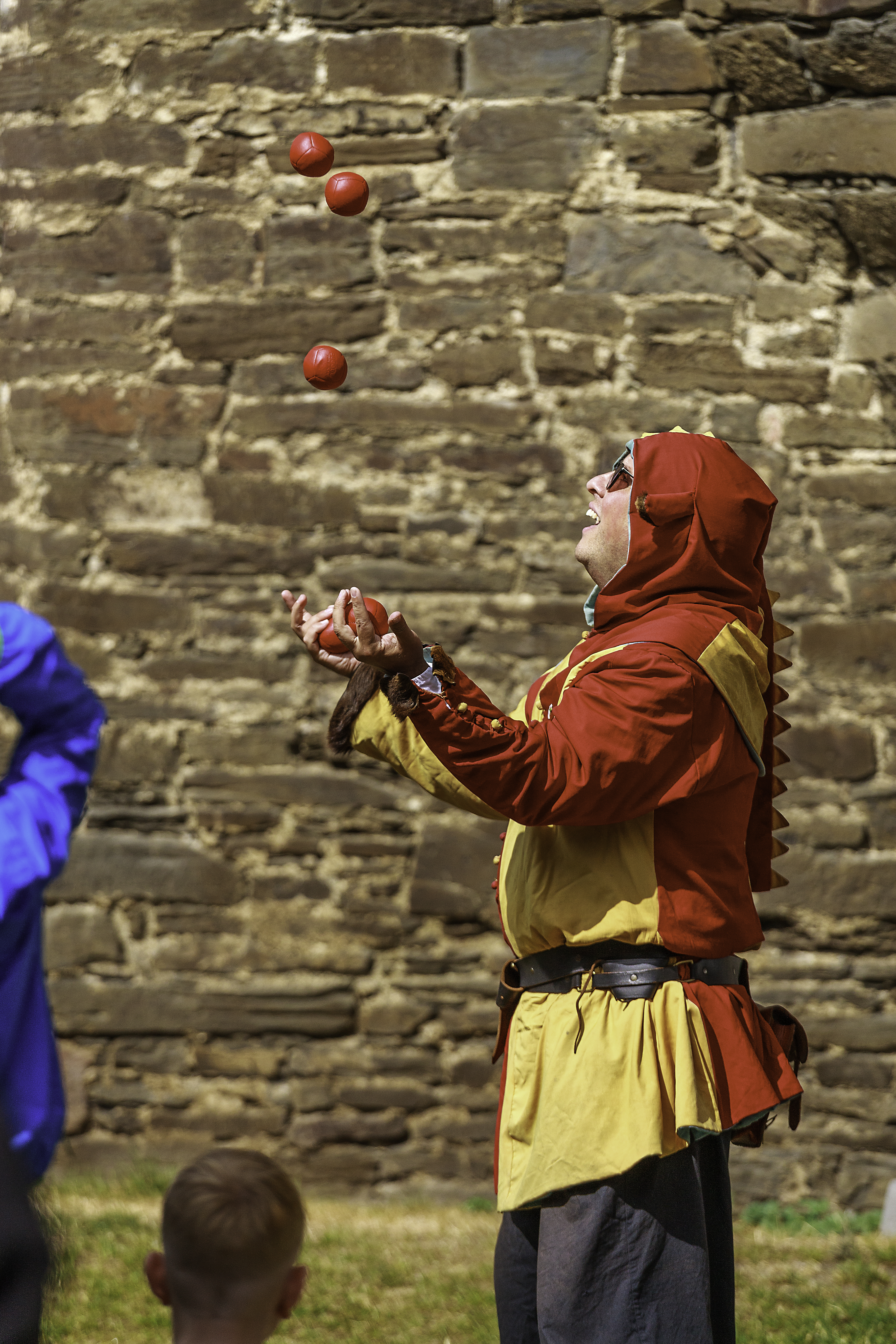 A juggler in costume juggling balls at Castle Conwy