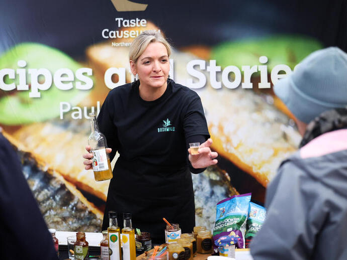 Woman at food stall offering drink samples to the public