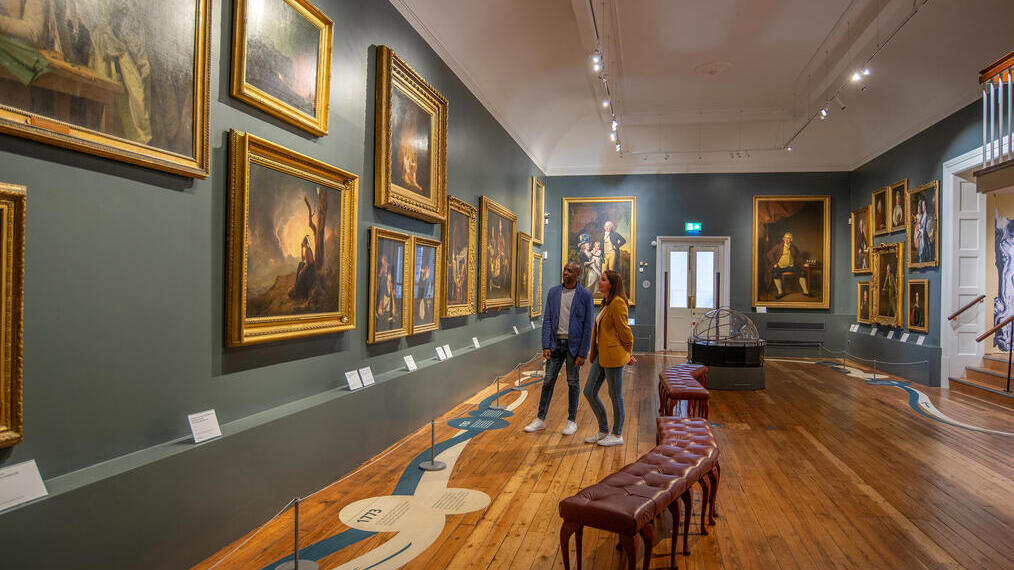 Un uomo e una donna guardano dei dipinti in una galleria