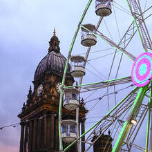 Looking up at clock tower and a Ferris wheel at dusk
