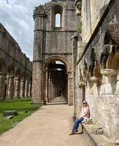Una mujer frente a la abadía Fountain Abbey en Studley Royal Park