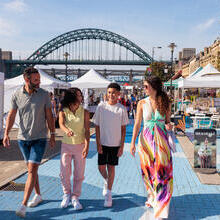 Family walking through stalls at a market in a city