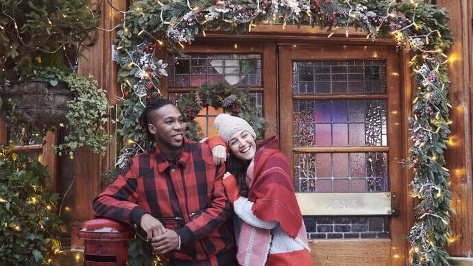 Couple in front of a pub entrance covered with Christmas decorations