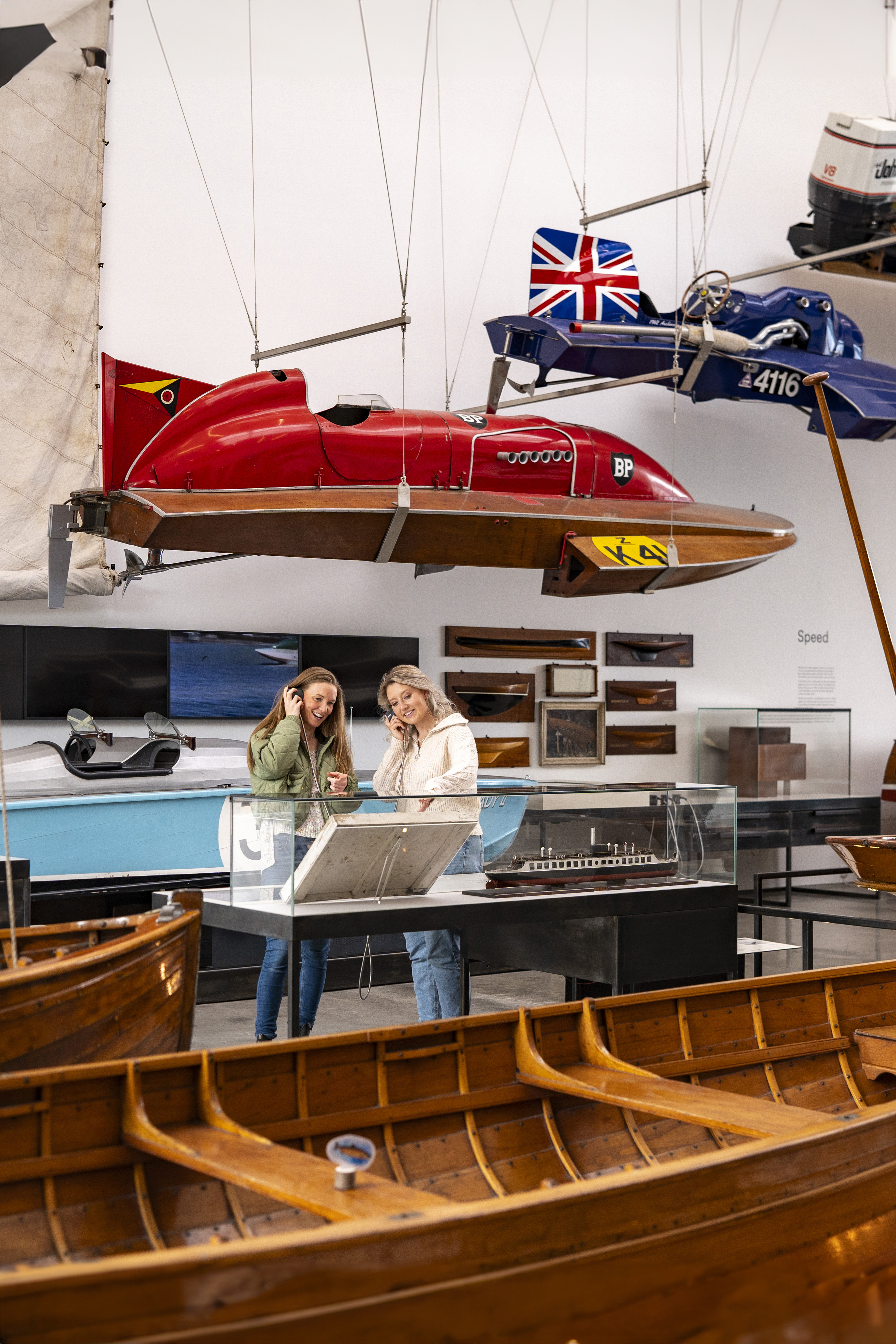Two women listen to an audio commentary in a museum