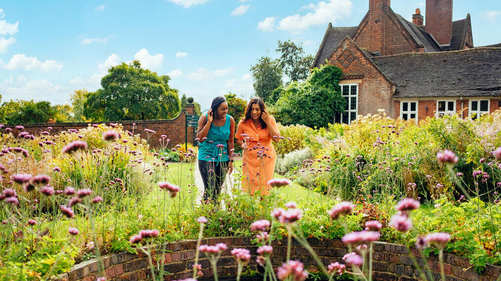 Two women walking through a garden filled with wildflowers