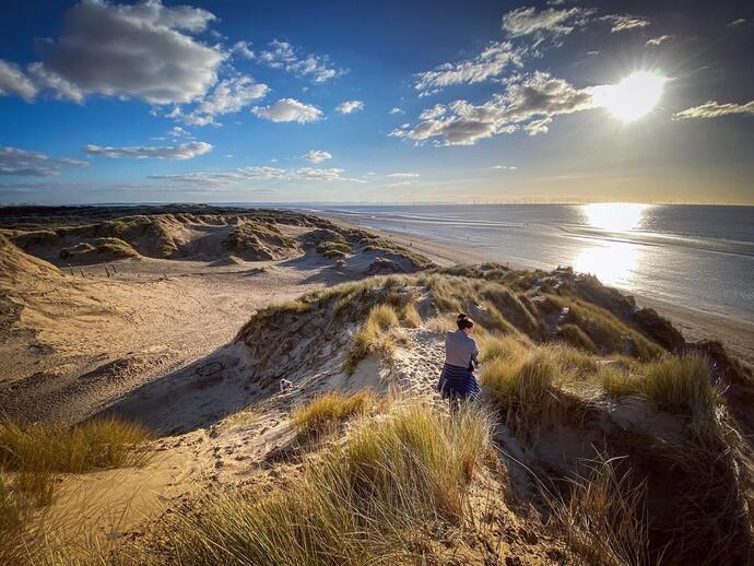 Woman walking along sand dunes at Formby beach