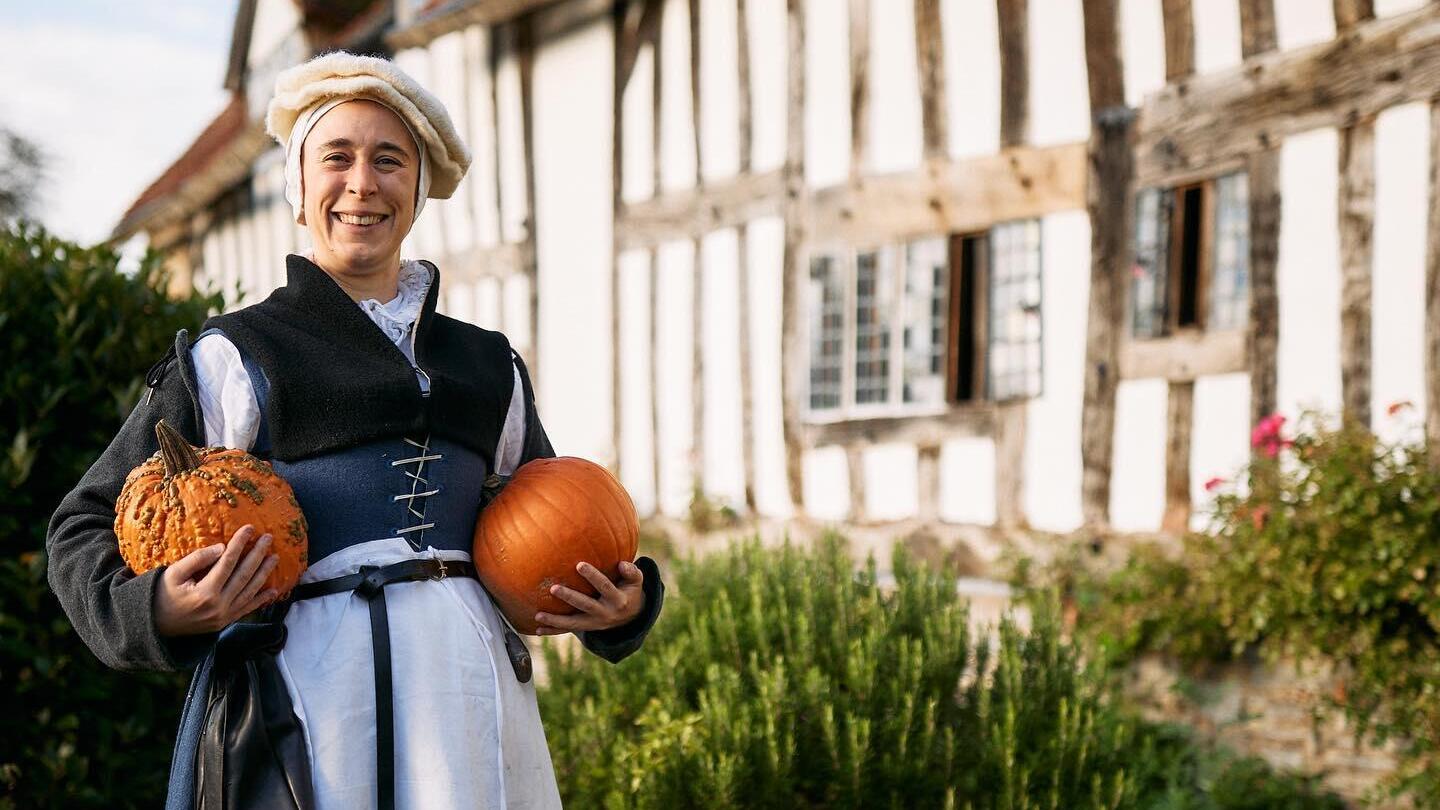 Una signora in piedi fuori dalla fattoria di Mary Arden