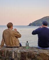 Due uomini che bevono gin guardando il mare
