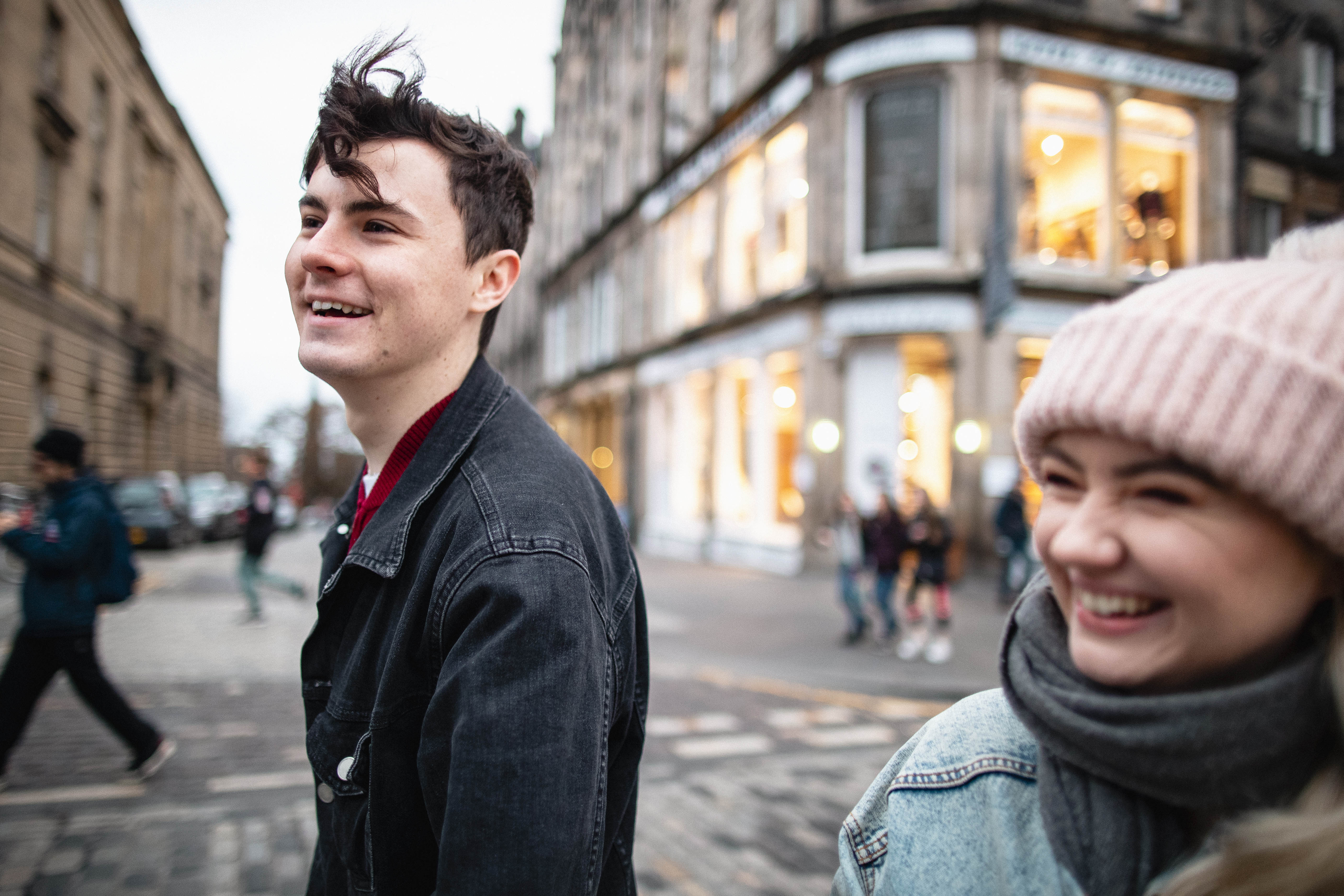 Young man and woman exploring city streets with shops in background